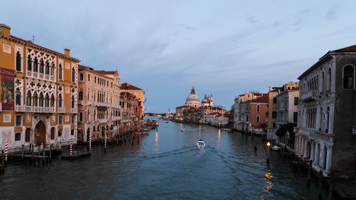 Canal amidst buildings in city against sky