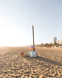 Rear view of man sitting on beach against clear sky