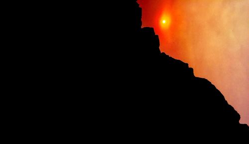 Silhouette cliff against sky at night