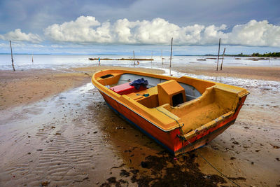 Boat moored on beach against sky