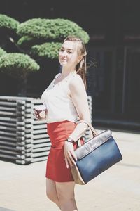 Woman holding a smiling while standing against wall