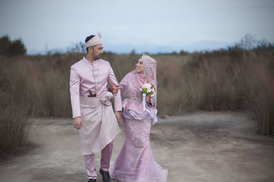 Bride and bridegroom wearing traditional clothing on field