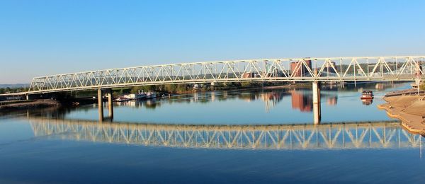 Reflection of people on bridge against clear blue sky