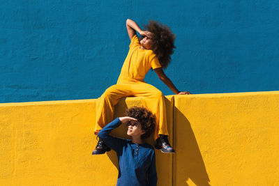 Young woman standing against yellow wall