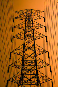 Low angle view of electricity pylon against sky during sunset