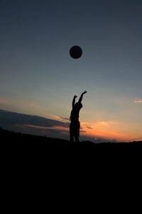 Silhouette man playing soccer against sky during sunset