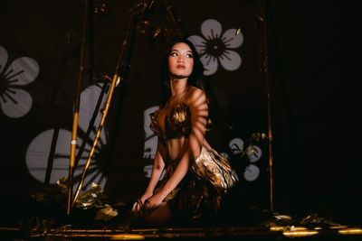 Portrait of young woman standing against sky at night