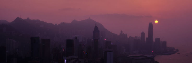 Silhouette of buildings in city at sunset