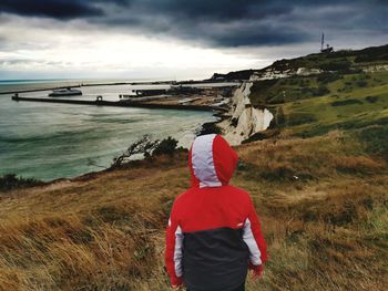 Rear view of boy  looking at sea against sky