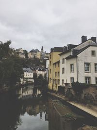 River amidst houses and trees against sky