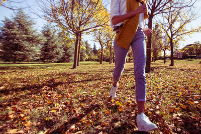 Low section of woman standing on field during autumn