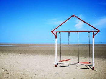 Lifeguard hut on beach against clear blue sky