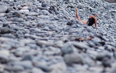 Shirtless man resting on pebbles at riverbank