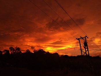 Silhouette electricity pylon against sky during sunset