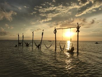 Holbox island - silhouette of wooden post in sea against sky during sunset