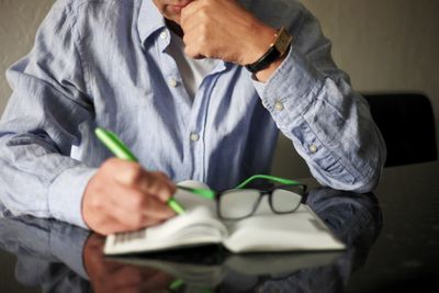 Midsection of man reading book while sitting on table