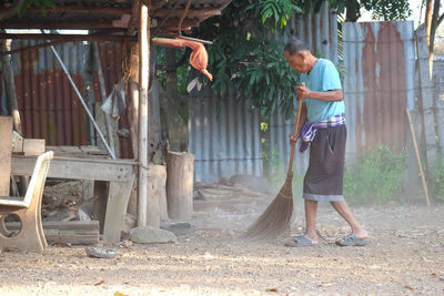 Side view of senior man sweeping land