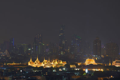 Illuminated city against clear sky at night