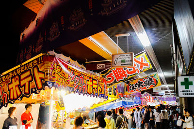 People at illuminated market in city at night
