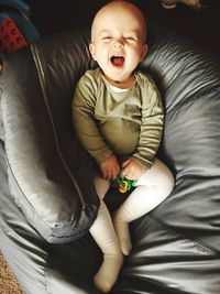 High angle view of laughing cute baby boy sitting on bean bag at home