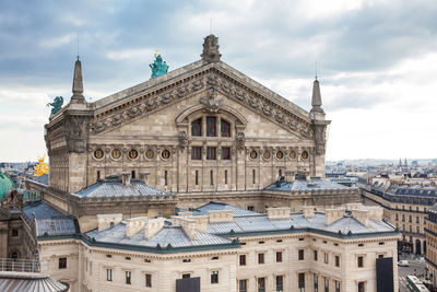 Buildings in city against cloudy sky