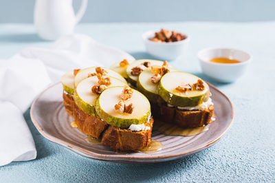 Appetizing sandwiches on rye bread with arugula, pear, honey and nuts on a plate