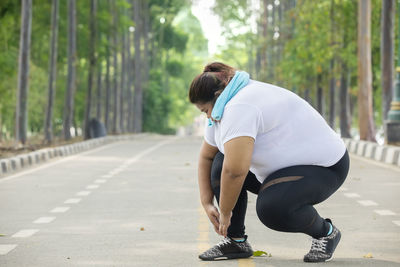 Overweight young woman tying shoelace at park