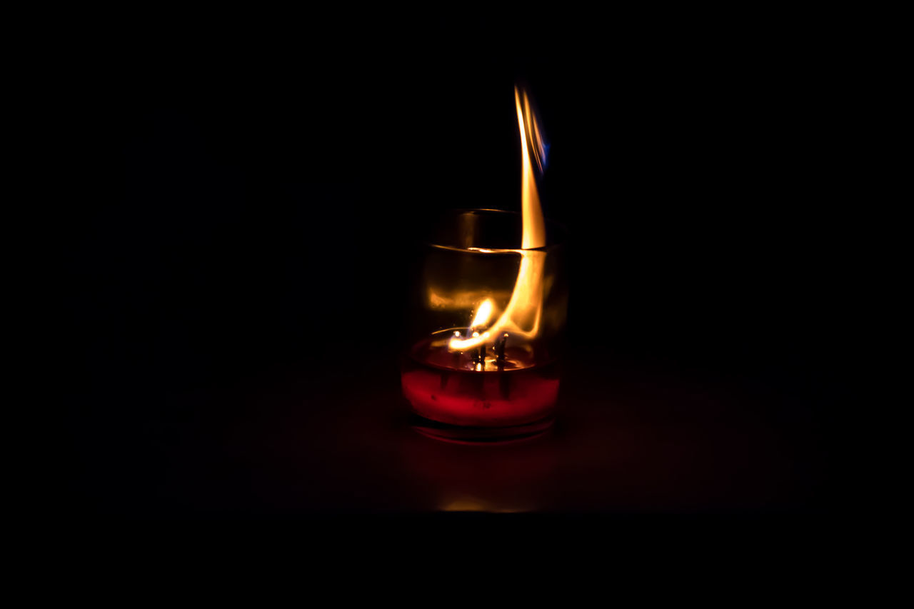 CLOSE-UP OF ILLUMINATED CANDLES ON BLACK BACKGROUND