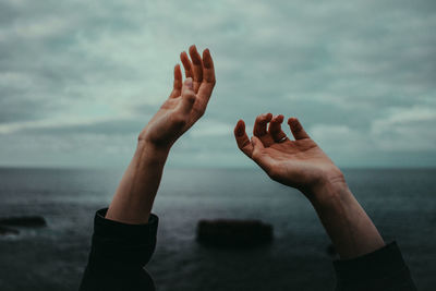 Close-up of cropped hands against sea