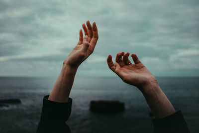 Close-up of woman hand on beach against sky