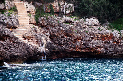 Rock formation and ladder by sea, cala d'or 