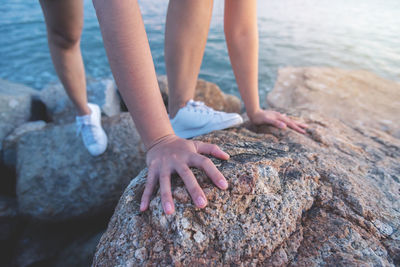 Midsection of woman on rock at sea shore