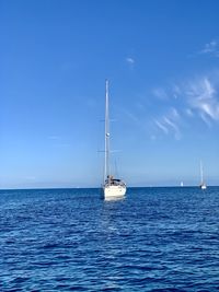 Sailboat sailing on sea against blue sky