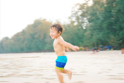 Full length of shirtless boy standing on beach