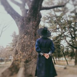 Rear view of man standing by tree trunk
