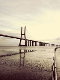 Bridge over calm sea against sky