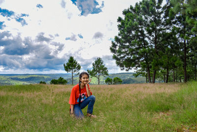 Portrait of smiling teenage girl kneeling on grassy field