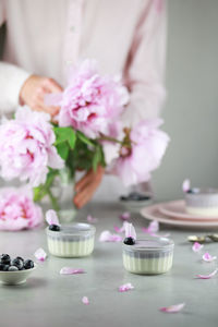 Homemade italian dessert panna cotta with blue berries, bouquet of peony flowers on gray background.