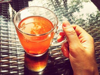 Close-up of hand holding drink on table