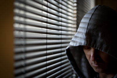 Close-up of man standing against window