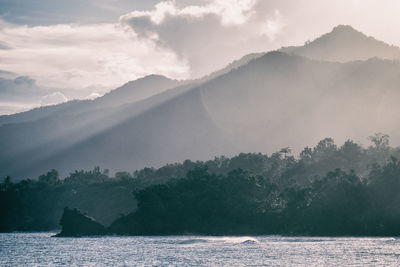 Scenic view of sea by mountains against sky