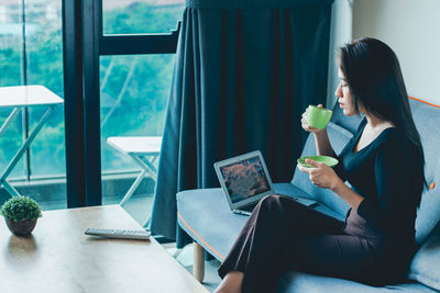 Woman using phone while sitting on table