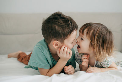 Older brother and younger sister playing in the bedroom on the bed. high quality photo