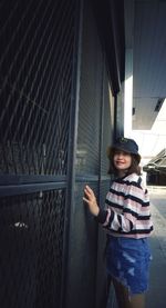 Portrait of smiling woman standing by fence