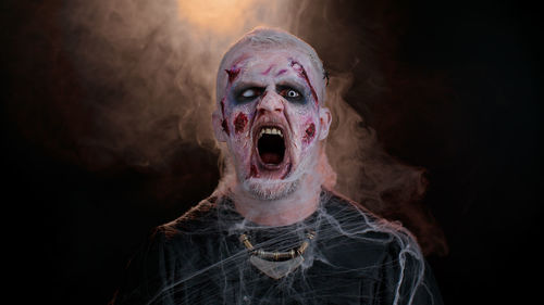 Portrait of man wearing mask against black background