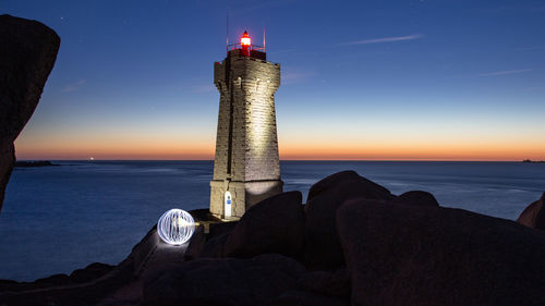 Lighthouse by sea against sky