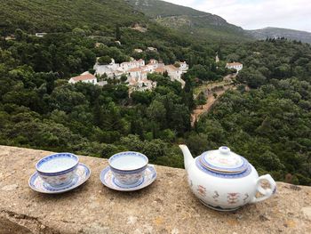 High angle view of kettle with tea cups and saucers on retaining wall