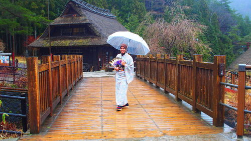 Woman standing on footbridge in rain