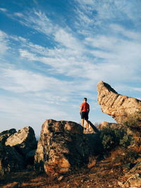 Man standing on rock against sky