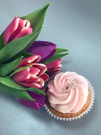 Close-up of cupcake by tulips on table